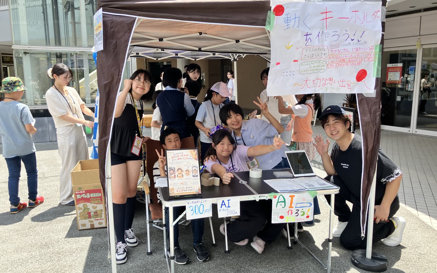 駅前PORTマルシェのブースで手書きの看板を掲げる子どもたち